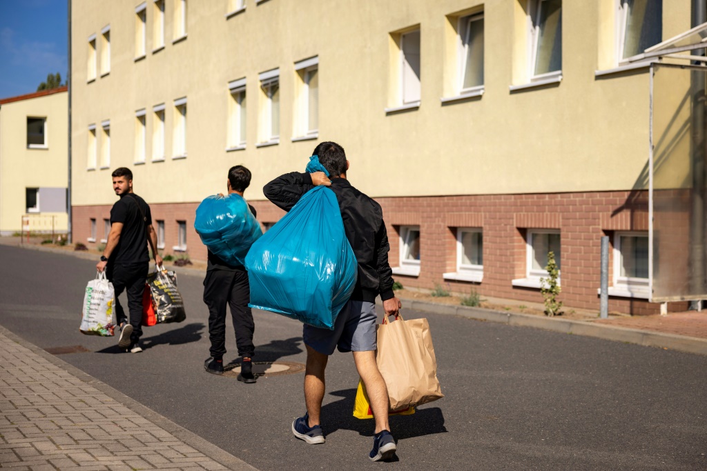 وافدون جدد أمام مبنى سكني في مركز هيئة الهجرة المركزية في براندنبورغ الذي يؤوي حوالي 1400 طالب لجوء في آيزنهوتنشتات، في شرق ألمانيا، في 28 أيلول/سبتمبر 2023 (أ ف ب)   
