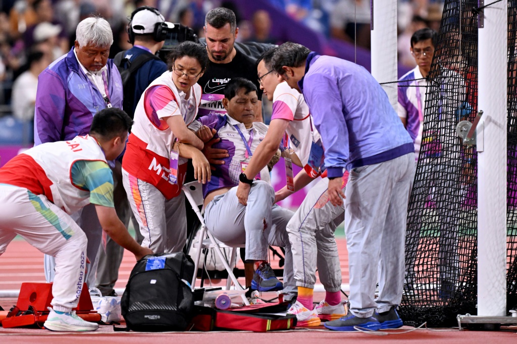 الحكم هوانغ تشين هوا يتلقى المساعدة بعد تعرضه لمطرقة ألقاها اللاعب الكويتي علي الزنكوي (في الخلف) دورة الألعاب الآسيوية المقامة في هانغجو الصينية (ا ف ب)