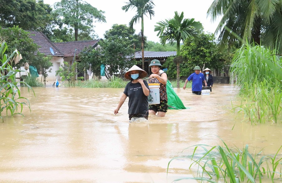 أشخاص يقومون باجتياز منطقة مغمورة بمياه الفيضانات في مقاطعة نغي آن بوسط فيتنام في 27 سبتمبر 2023 (شينخوا)