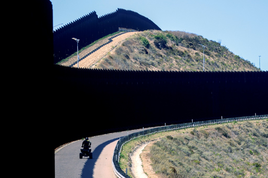 يقوم أحد عملاء الجمارك وحرس الحدود الأمريكي بدوريات على السياج على طول الحدود مع المكسيك (أ ف ب)