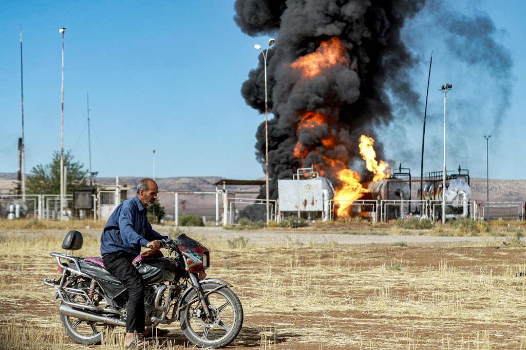     رجل يستعد لركوب دراجة نارية بالقرب من حريق مشتعل في منشأة نفطية في القحطانية شمال شرق سوريا قرب الحدود التركية في 5 تشرين الأول/أكتوبر 2023 (ا ف ب)   