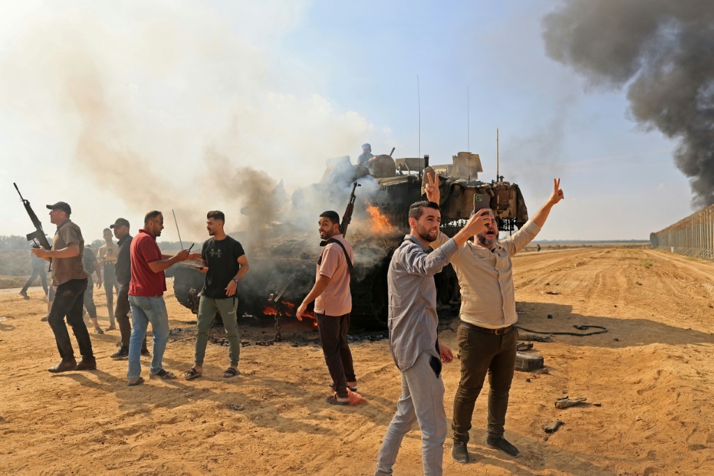      فلسطينيون يسيطرون على دبابة إسرائيلية بعد عبور السياج الحدودي مع إسرائيل من خان يونس جنوب قطاع غزة (أ ف ب)   