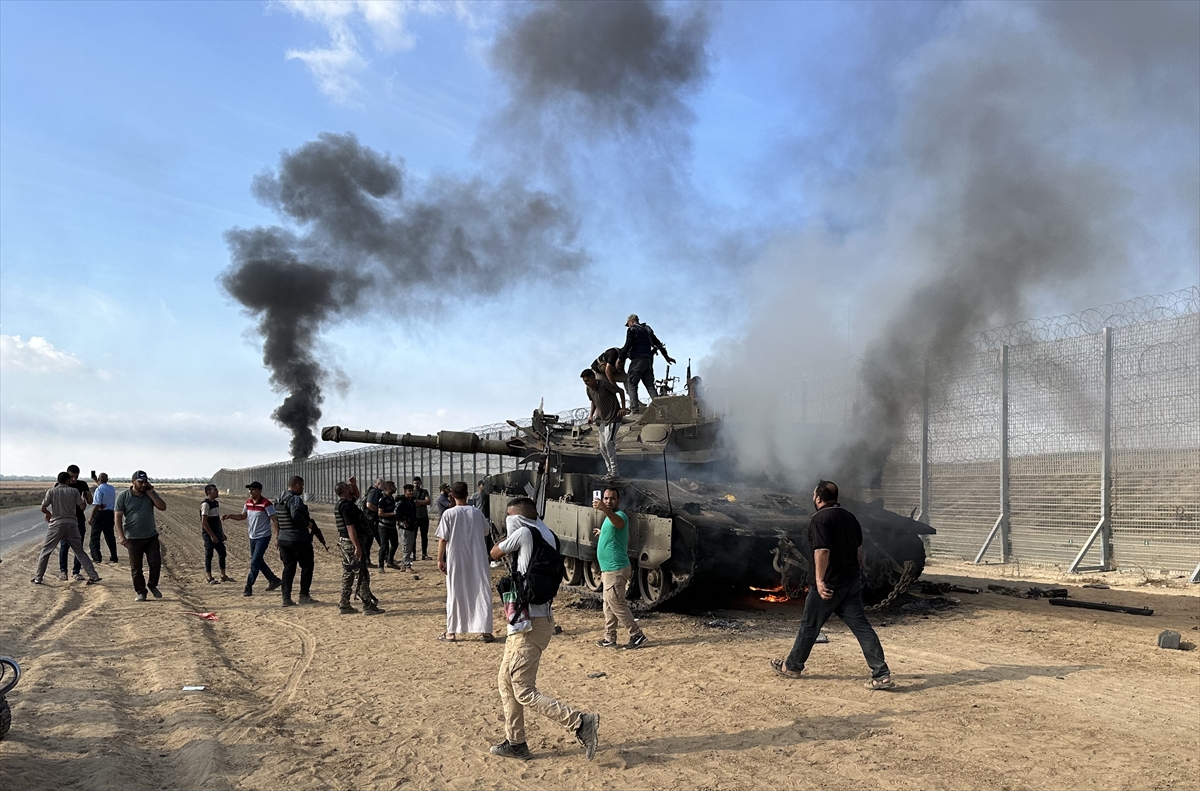 فلسطينيون يحتفلون أمام دبابة إسرائيلية تم تدميرها من قبل المقاومة (الأناضول)