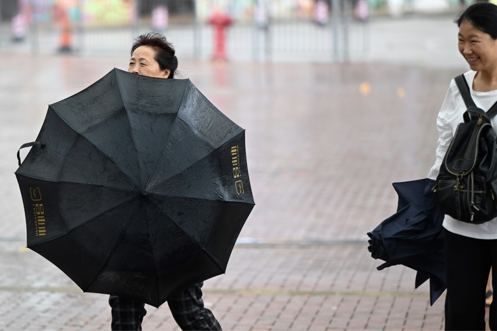 امرأة تحاول مقاومة الرياح بمظلتها تزامنا مع مرور الاعصار كوينو في هونغ كونغ في الثامن من تشرين الاول/اكتوبر 2023 (ا ف ب)
