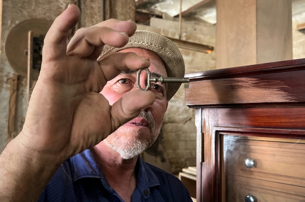 الحرفي رينيه رييس يتفحص مفتاح صتدوق لترطيب السيجار في ورشة عمله في العاصمة الكوبية هافانا في 5 أيلول/سبتمبر 2023 (ا ف ب)