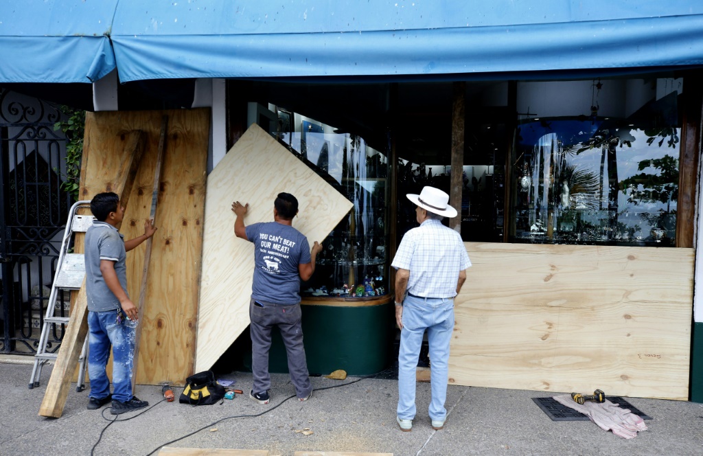 أصحاب المتاجر في مدينة بويرتو فالارتا الساحلية في المكسيك يغلقون النوافذ مع اقتراب إعصار ليديا (ا ف ب)