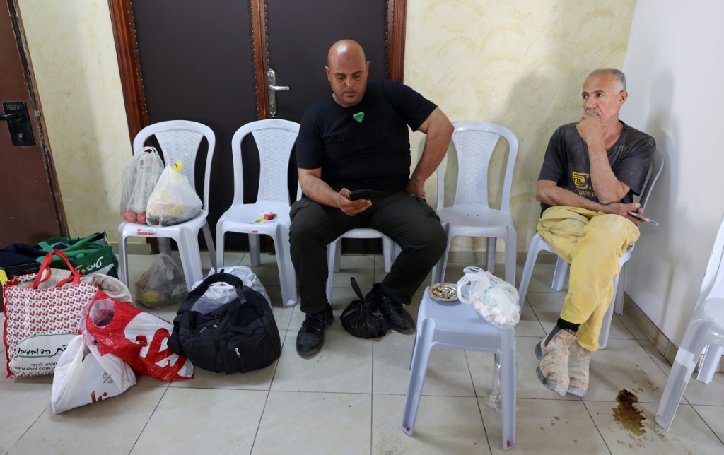 فلسطينيون من غزة تقطعت بهم السبل في الضفة الغربية التي تحتلها إسرائيل، يتابعون الأخبار في غرفة فندق في رام الله (ا ف ب)   