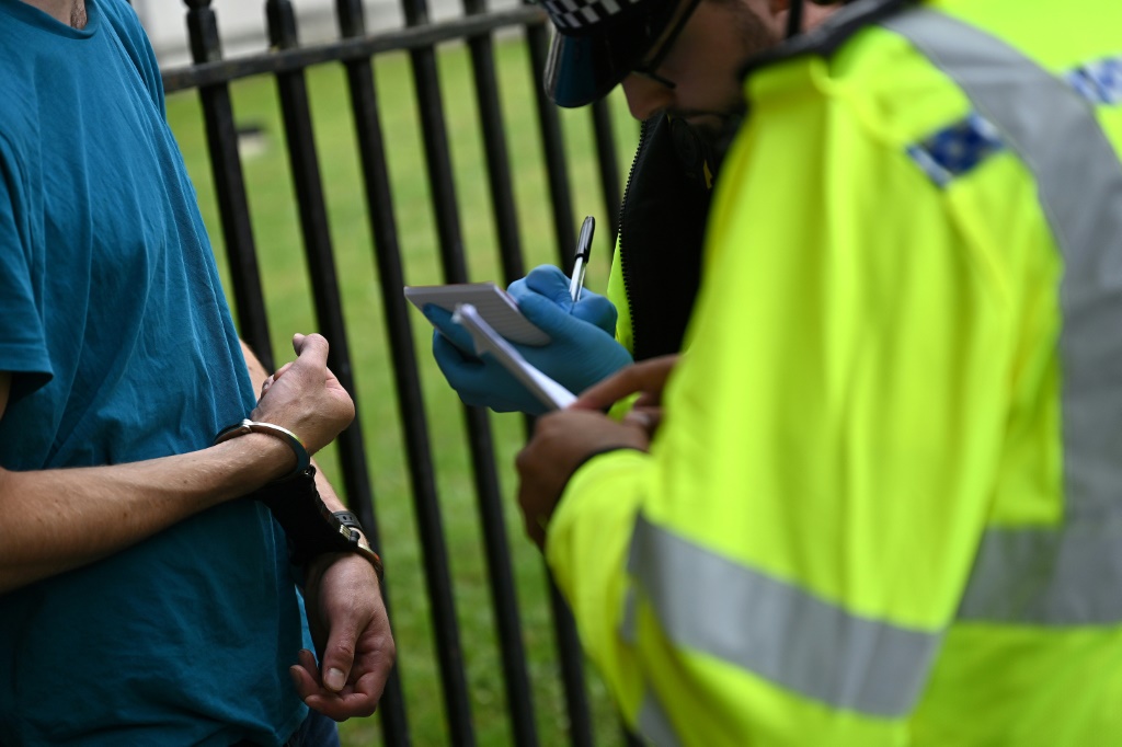 عنصر من الشرطة يدوّن ملاحظات بعد توقيف أحد الناشطين في مجال المناخ في لندن بتاريخ 19 تموز/يوليو 2023 (ا ف ب)