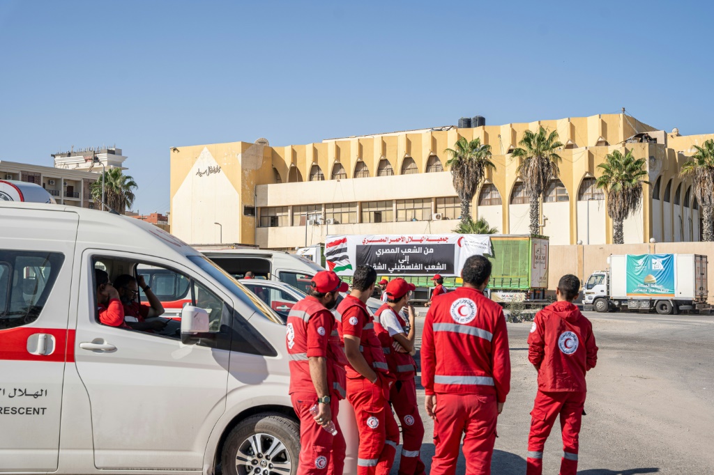 مسعفون وقافلة من الشاحنات المحملة بإمدادات المساعدات لغزة المقدمة من المنظمات غير الحكومية المصرية في انتظار التوصل إلى اتفاق للعبور عبر الحدود بين مصر وغزة (أ ف ب)  &nbsp;
