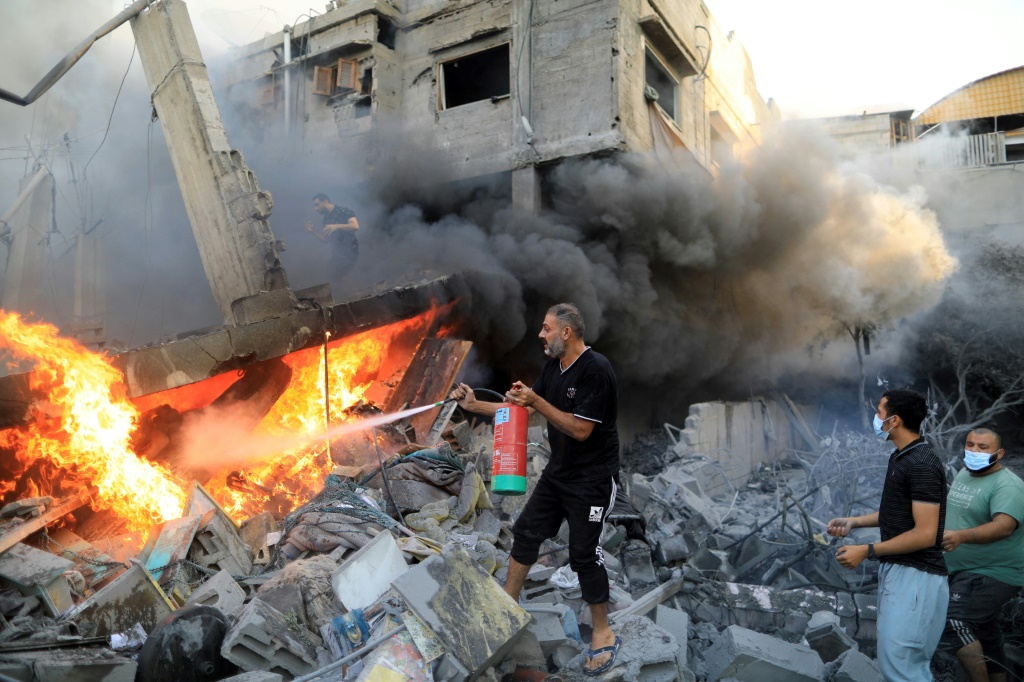 رجل فلسطيني يستخدم طفاية حريق لإخماد حريق عقب غارة إسرائيلية في خان يونس جنوب قطاع غزة (أ ف ب)  &nbsp;