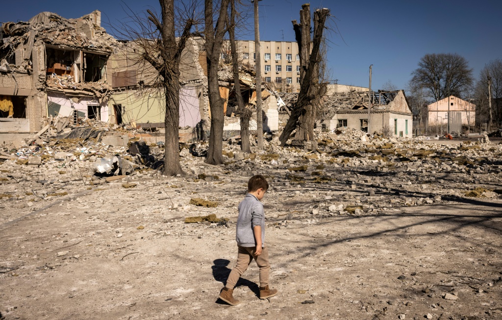 طفل يسير أمام مدرسة مدمرة في مدينة زيتومير في شمال أوكرانيا في 23 آذار/مارس 2023 (ا ف ب)   