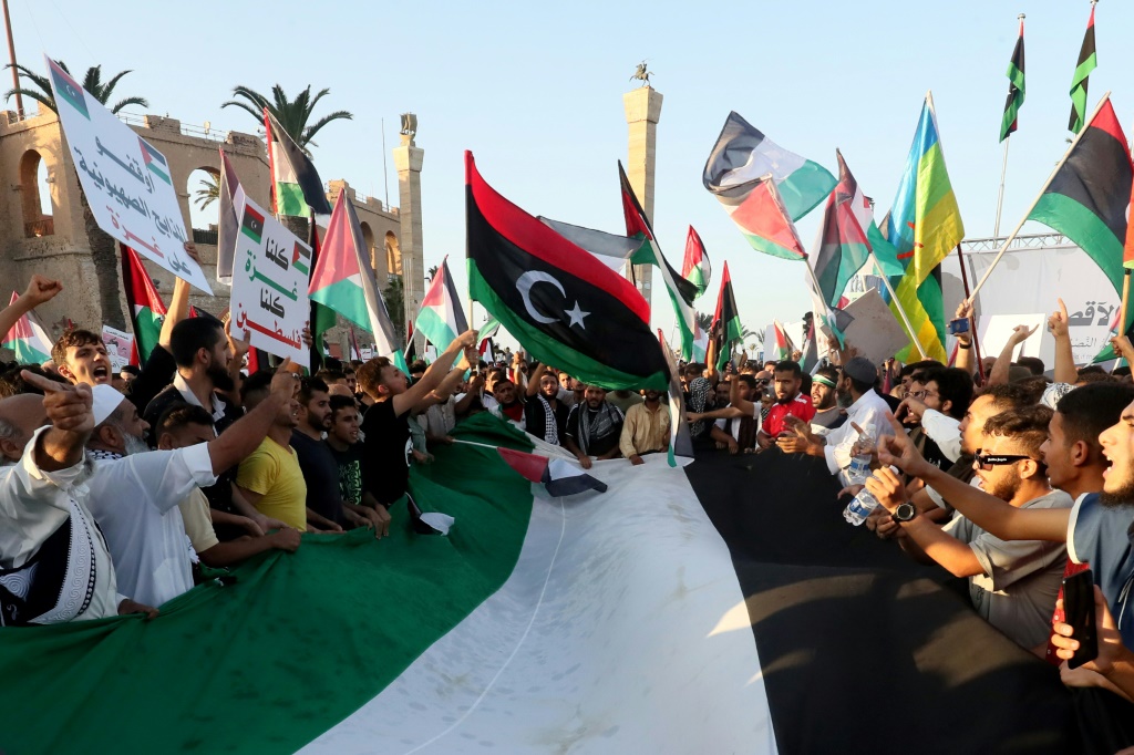 ليبيون يرددون الشعارات ويلوحون بالأعلام الوطنية الفلسطينية والليبية وهم يسيرون تضامنا مع شعب فلسطين (ا ف ب)   