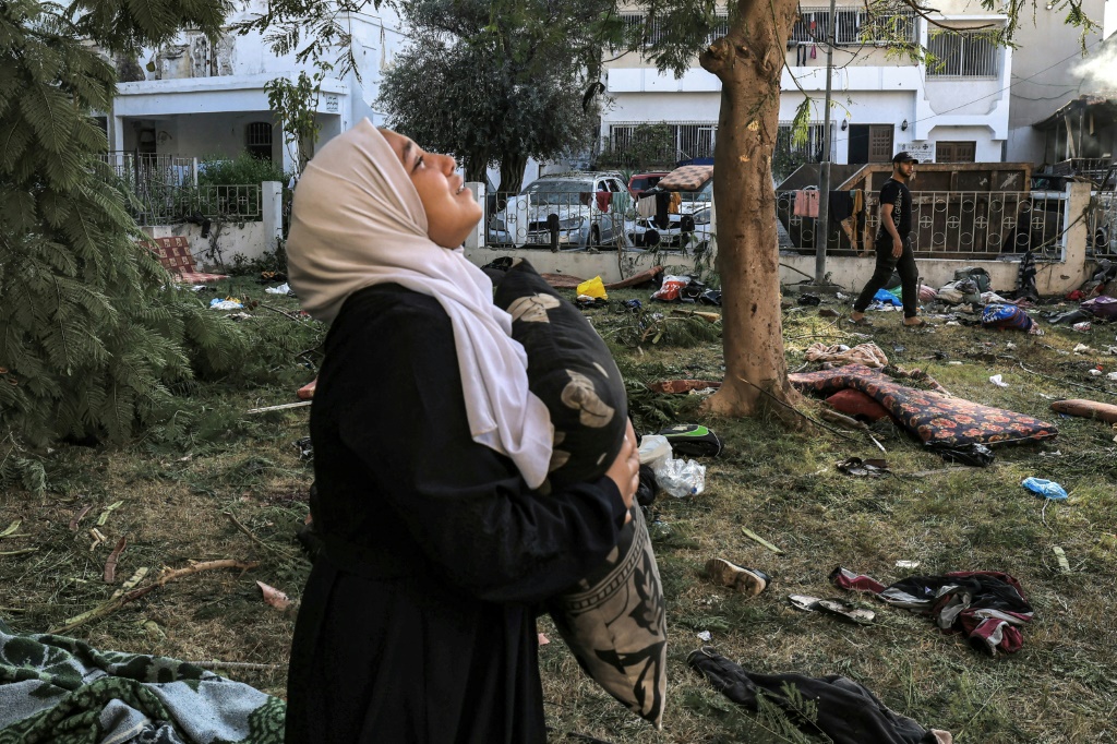 امرأة تبكي وهي تحمل وسادة وتقف وسط الأنقاض خارج موقع المستشفى الأهلي العربي في وسط غزة في 18 تشرين الأول/أكتوبر 2023 في أعقاب قصف أوقع مئات القتلى فيه (أ ف ب)  &nbsp;