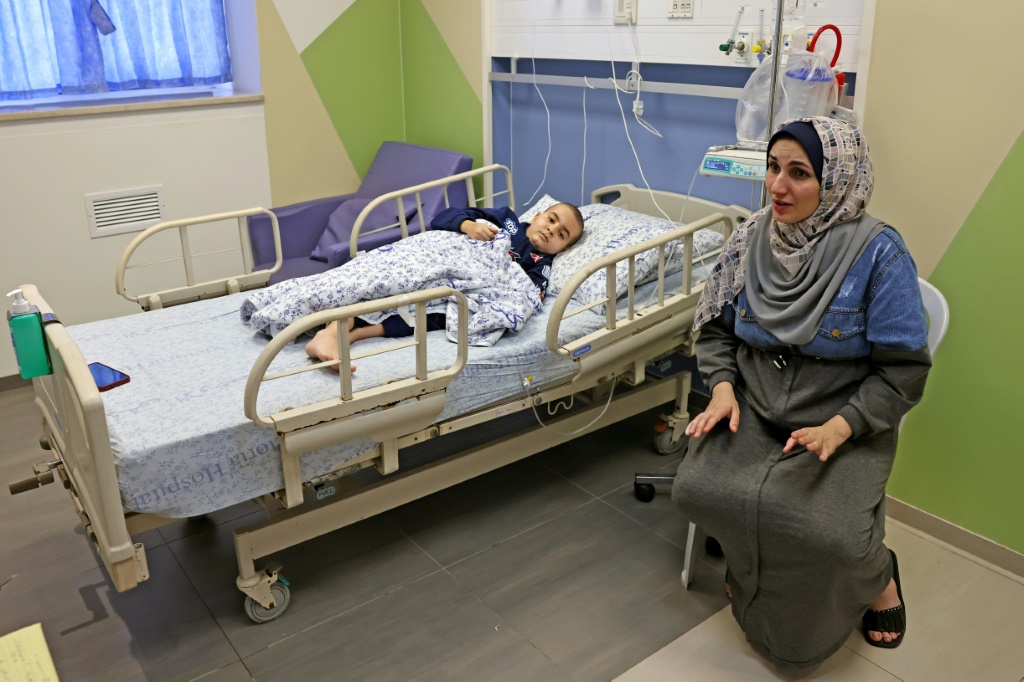 الفلطسينية مي زين الدين من قطاع غزة تجلس بجوار ابنها علي المصاب بالسرطان في مستشفى اوغستا فيكتوريا في الدقس الشرقية في 17 تشرين ألول/أكتوبر 2023 مع استمرار الحرب بين اسرائيل وحركة حماس (ا ف ب)