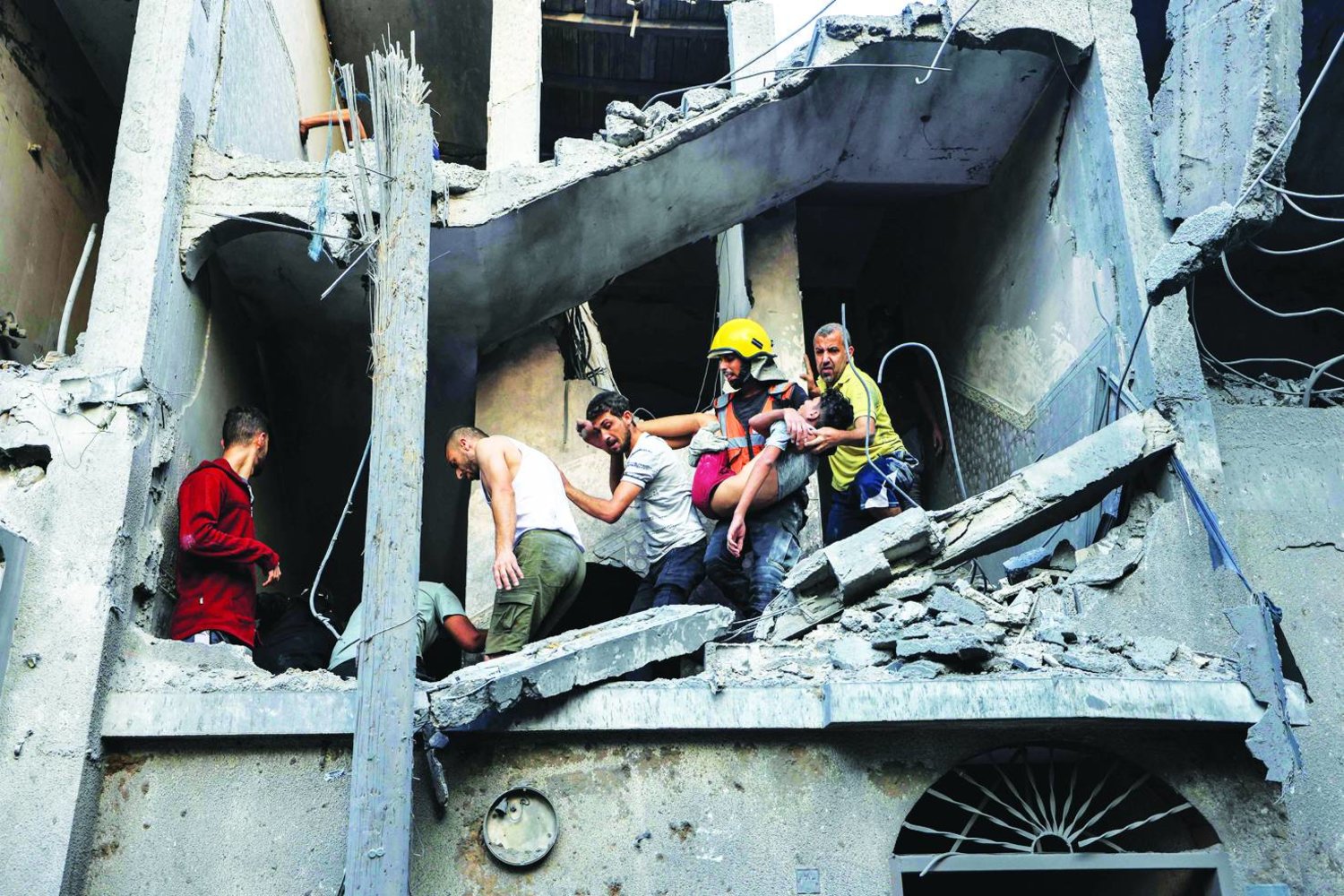 فلسطينيون يجلون شاباً جرى إنقاذه من ركام بناية طالها القصف الإسرائيلي في خان يونس بجنوب غزة الخميس (أ.ف.ب)