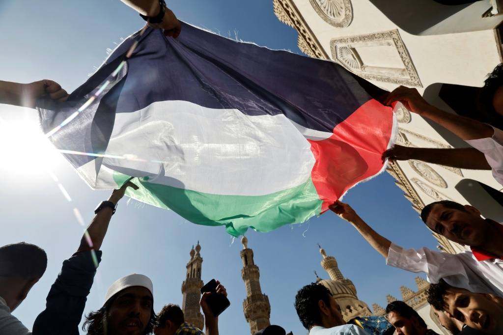 أشخاص يرفعون العلم الفلسطيني خلال تظاهرة تضامنية مع الشعب الفلسطيني بعد صلاة الجمعة خارج الجامع الأزهر في القاهرة في 20 تشرين الأول/أكتوبر 2023 (ا ف ب)