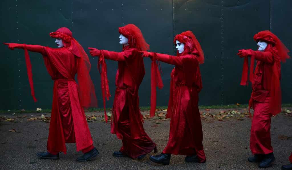 أفراد من مجموعة "التمرد على الانقراض" يؤدون عرضًا خلال مسيرة من أجل المناخ في لندن، في 19 تشرين الأول/أكتوبر 2023، خلال أسبوع من التظاهرات التي نظمها نشطاء المناخ (أ ف ب)   