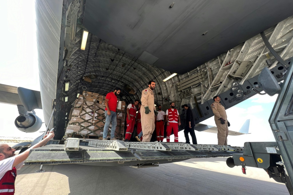 متطوعون من قطر والهلال الأحمر المصري يفرغون مساعدات متجهة إلى قطاع غزة في مطار العريش المصري (أ ف ب)   