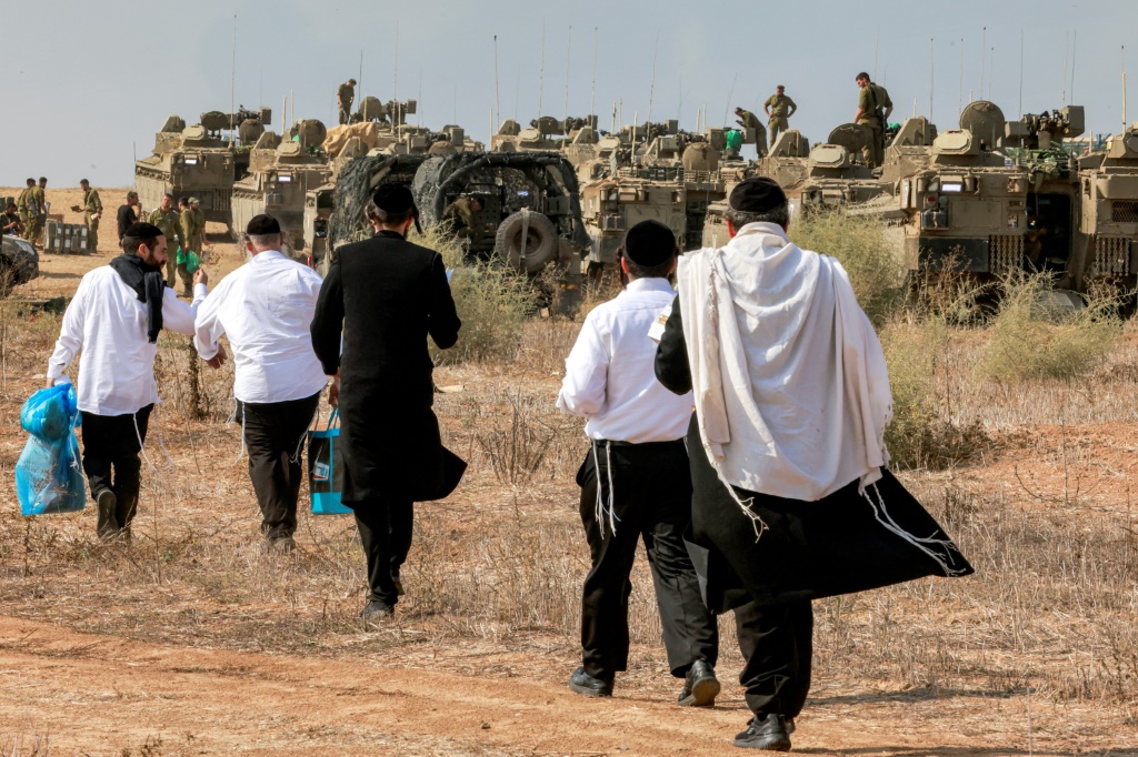 اليهود المتدينون يزورون جنود الجيش الإسرائيلي لإظهار دعمهم أثناء انتشارهم في موقع بالقرب من الحدود مع غزة في جنوب إسرائيل، 11 أكتوبر، 2023. (أ ف ب)   