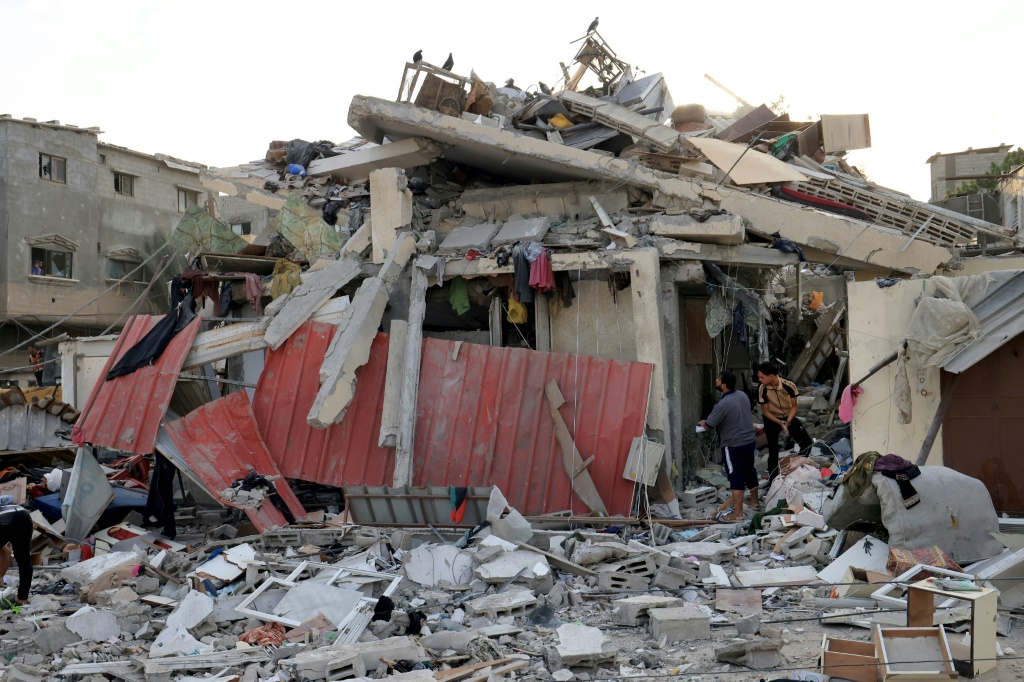 فلسطينيون ينظرون بين أنقاض مبنى بعد القصف الإسرائيلي على مدينة خان يونس جنوب قطاع غزة (أ ف ب)  &nbsp;