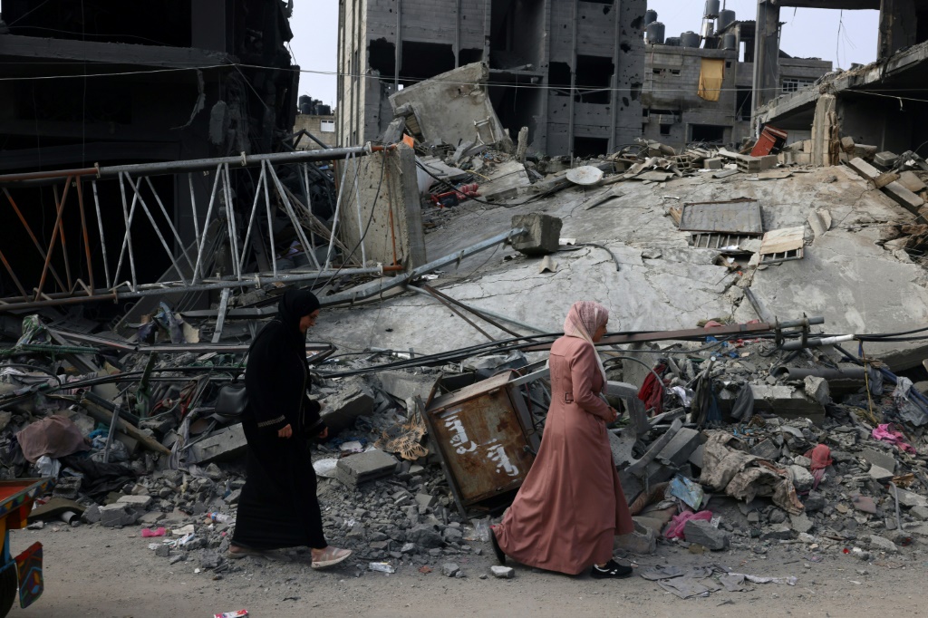 امراة تمر اما انقاض مبنى في رفح في جنوب قطاع غزة الذي يترعض لقصف إسرائيلي كثيف في 28 تشرين الأول/أكتوبر 2023 (ا ف ب)