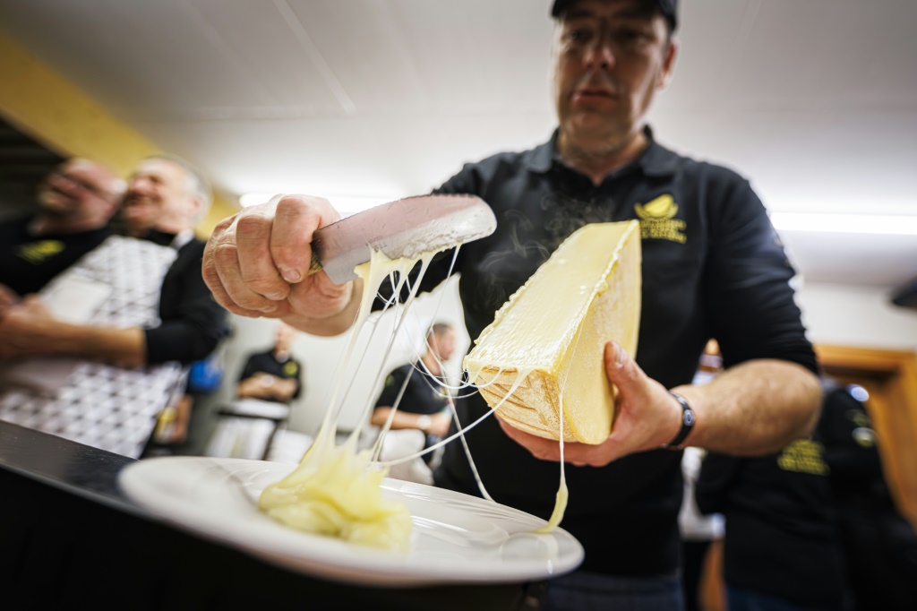 شخص يتولّى إزالة الجبنة الذائبة من أحد القوالب في مورجان السويسرية بتاريخ 28 تشرين الأول/أكتوبر 2023 (ا ف ب)