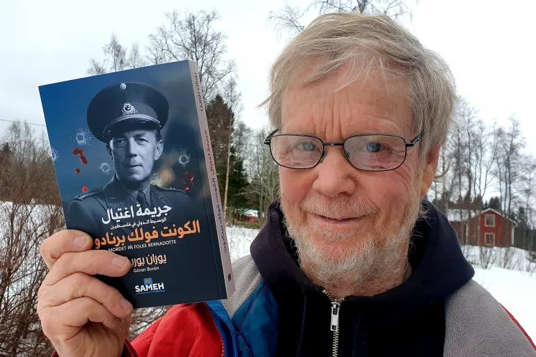 مؤلف الكتاب السويدي يوران بورين يحمل نسخة من الترجمة العربية (الجزيرة)