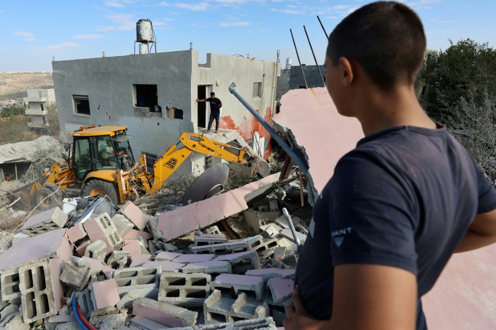 فلسطينيون ينظرون إلى حفارة تزيل أنقاض منزل الرجل الثاني في حماس المنفي صالح العاروري في الضفة الغربية بعد أن هدمته القوات الإسرائيلية (أ ف ب)  &nbsp;