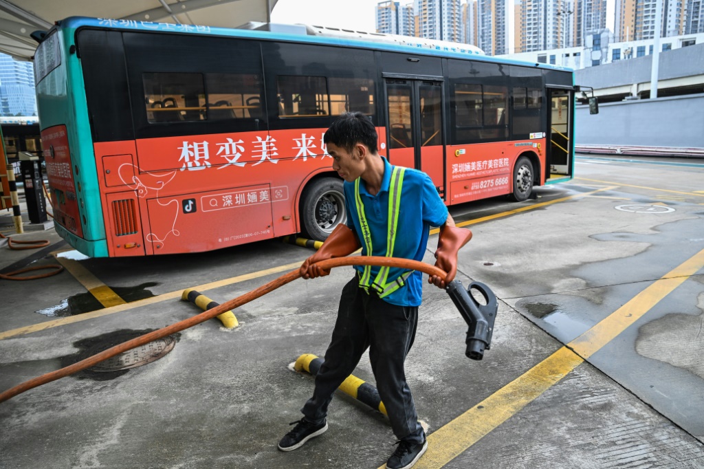 عامل يحمل كابل شحن قرب حافلة كهربائية يف مدينة شنجن الصينية في 18 تشرين الأول/أكتوبر 2023 (ا ف ب)