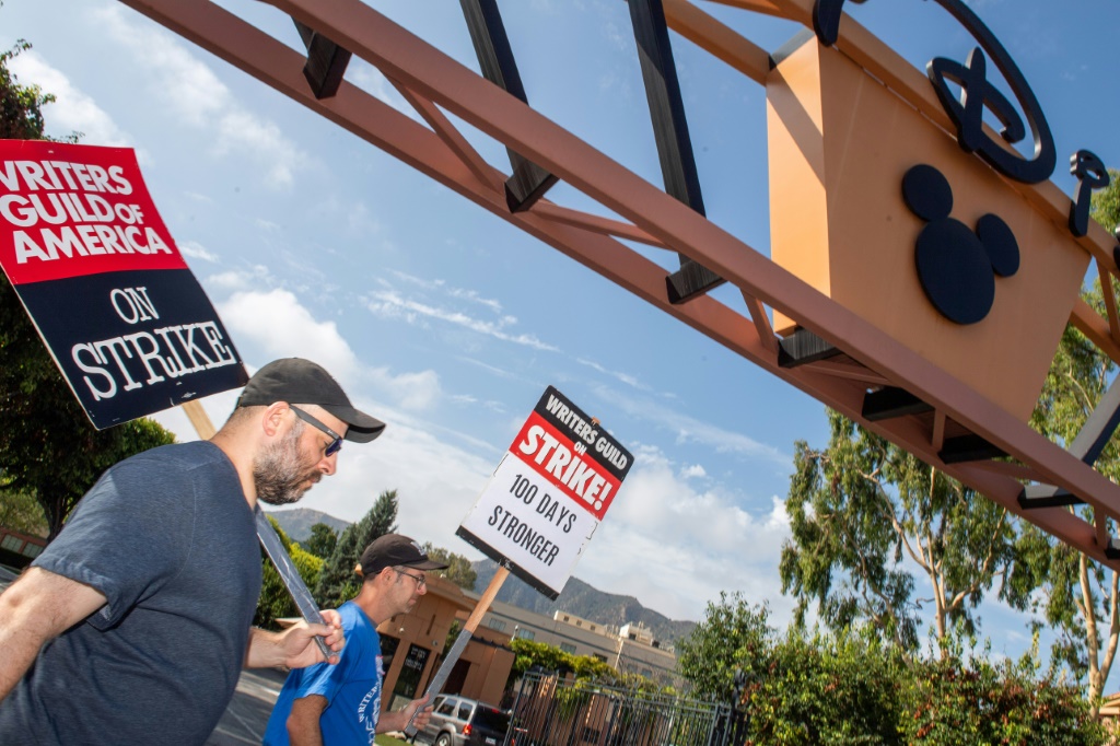 عضوان في نقابة كتّاب السيناريو في أميركا يحملان لافتتين أمام مقر استوديوهات ديزني في بوربانك بولاية كاليفورنيا الأميركية في التاسع من آب/أغسطس 2023 (ا ف ب)