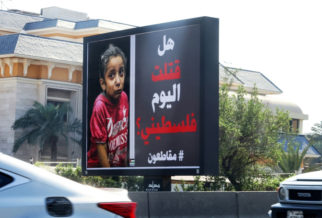    سيارات تمر أمام لوحة إعلانية في مدينة الكويت تظهر أطفالاً فلسطينيين وشعار: "قتلتم اليوم فلسطينياً؟ #قاطعوا" (ا ف ب)   