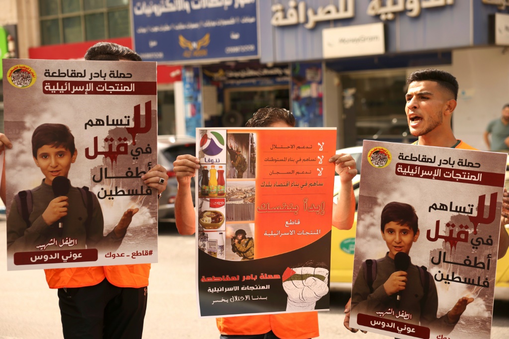 فلسطينيون يحملون لافتات تدعو لمقاطعة المنتجات الإٍسرائيلية خلال تجمع في الضفة الغربية المحتلة في 28 تشرين الأول/أكتوبر 2023 (ا ف ب)