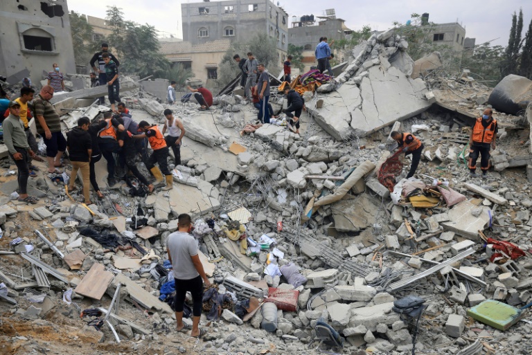 مدنيون ومسعفون يبحثون عن ناجين وسط ركام مبنى مدمر  في غزة (أ ف ب)