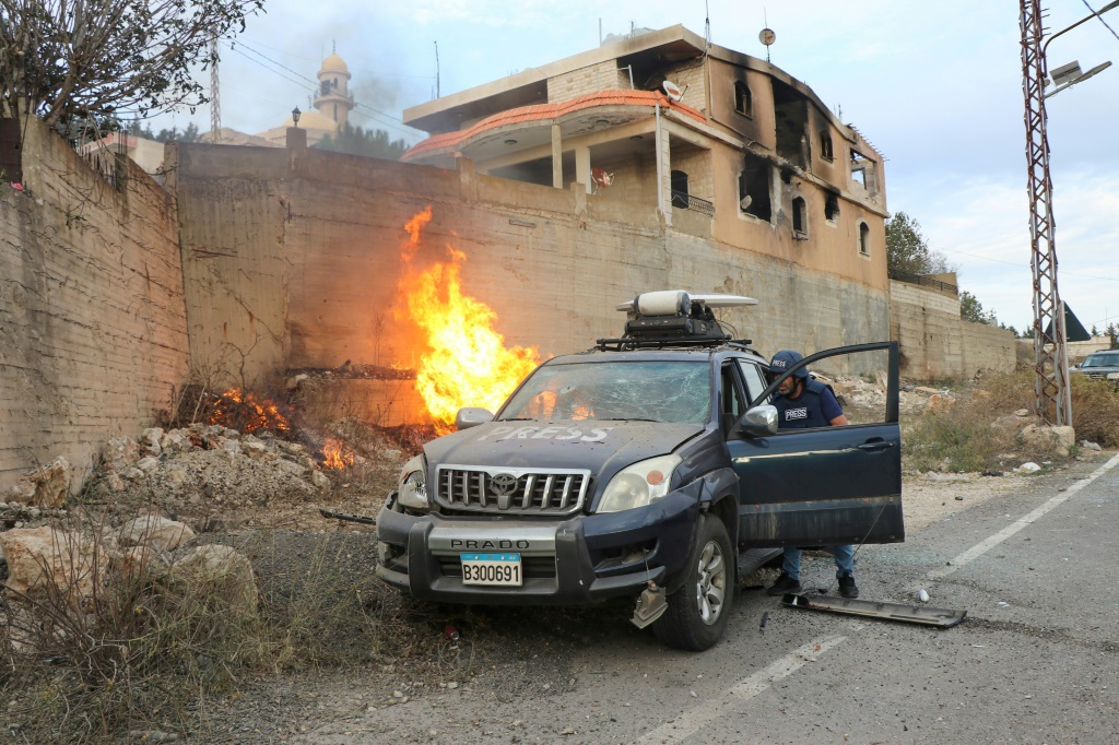 ألسنة اللهب بالقرب من سيارة صحفية في قرية يارون الحدودية بجنوب لبنان (أ ف ب)   