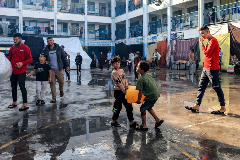 طفلان يحملان عبوة من المياة في ساحة مدرسة تابعة للأمم المتحدة في رفح في جنوب قطاع غزة في 14 تشرين الثاني/نوفمبر 2023 (أ ف ب)