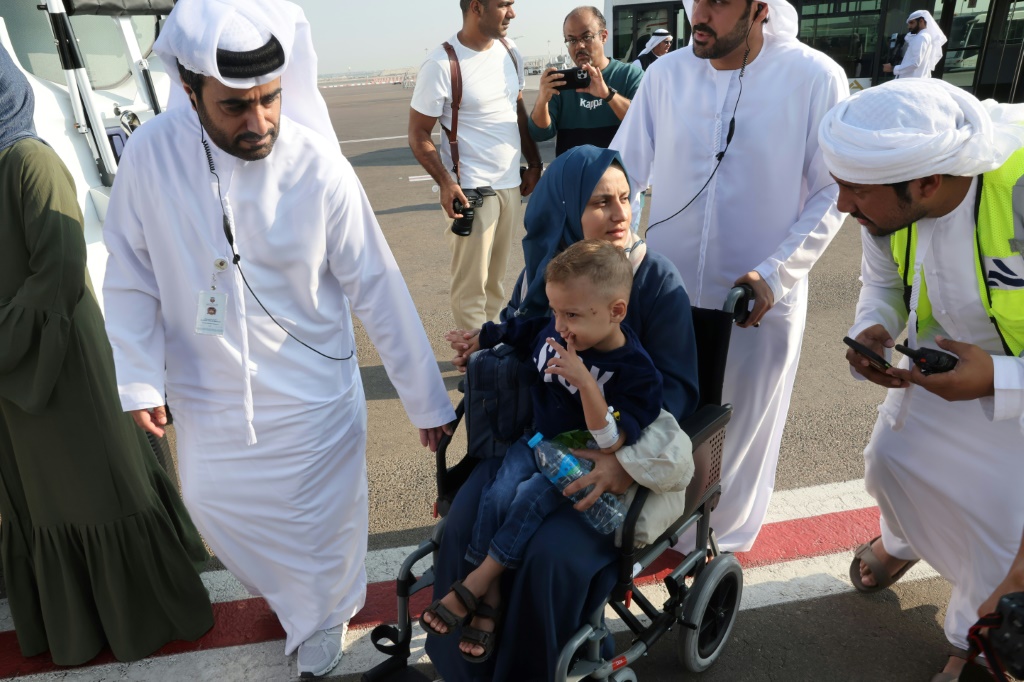 مسؤولون إماراتيون يتحثون مع امرأة فلسطينية تحمل ابنها على كرسي متحرك لدى وصولهما إلى أبوظبي في 18 تشرين الثاني/نوفمبر 2023 (ا ف ب)