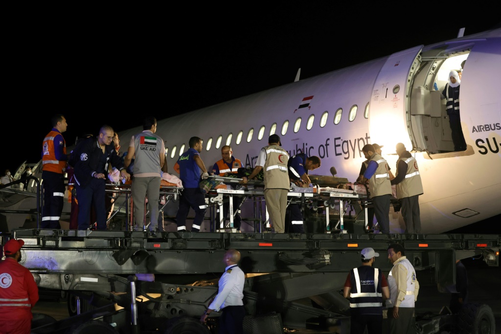  متطوعون يحملون أطفال فلسطينيون جرحى لإدخالهم إلى طائرة في مطار العريش قبيل إجلائهم إلى أبوظبي فجر 18 تشرين الثاني/نوفمبر 2023 (ا ف ب)