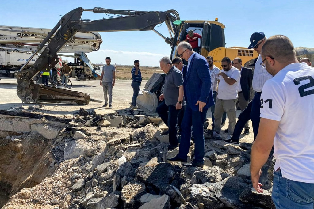  رئيس الوزراء السوري حسين عرنوس يتفقد الأضرار التي لحقت بمدرج مطار دمشق الدولي في 13 تشرين الأول/أكتوبر 2023 بعد غارة جوية إسرائيلية (سانا- أ ف ب)  