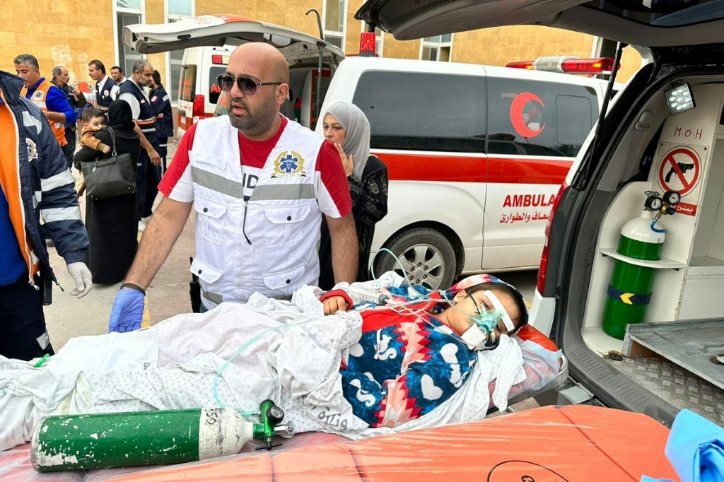 مسعفون مصريون ينقلون طفلة فلسطينية مصابة إلى سيارة إسعاف تابعة للهلال الأحمر لدى وصولها من غزة عبر معبر رفح الحدودي (ا ف ب)