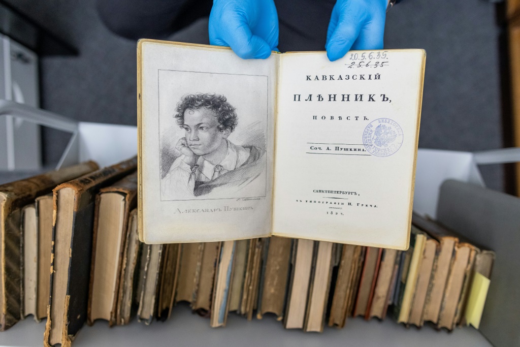موظف يحمل نسخة مزيفة من الطبعة الأولى لكتاب من عام 1822 للكاتب ألكسندر بوشكين في مكتبة جامعة وارسو البولندية في 14 تشرين الثاني/نوفمبر 2023 (ا ف ب)