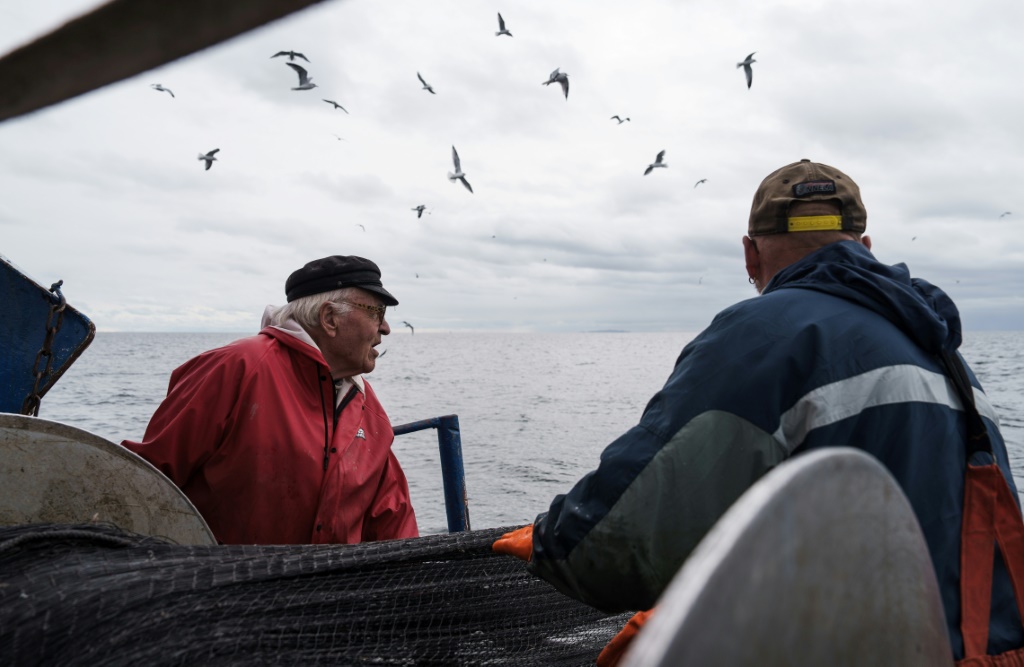 الصياد هولغر شوغرن (شمال) على متن قاربه قبالة ساحل كوتكا في جنوب فنلندا بتاريخ العاشر من تشرين الاول/اكتوبر 2023 (ا ف ب)