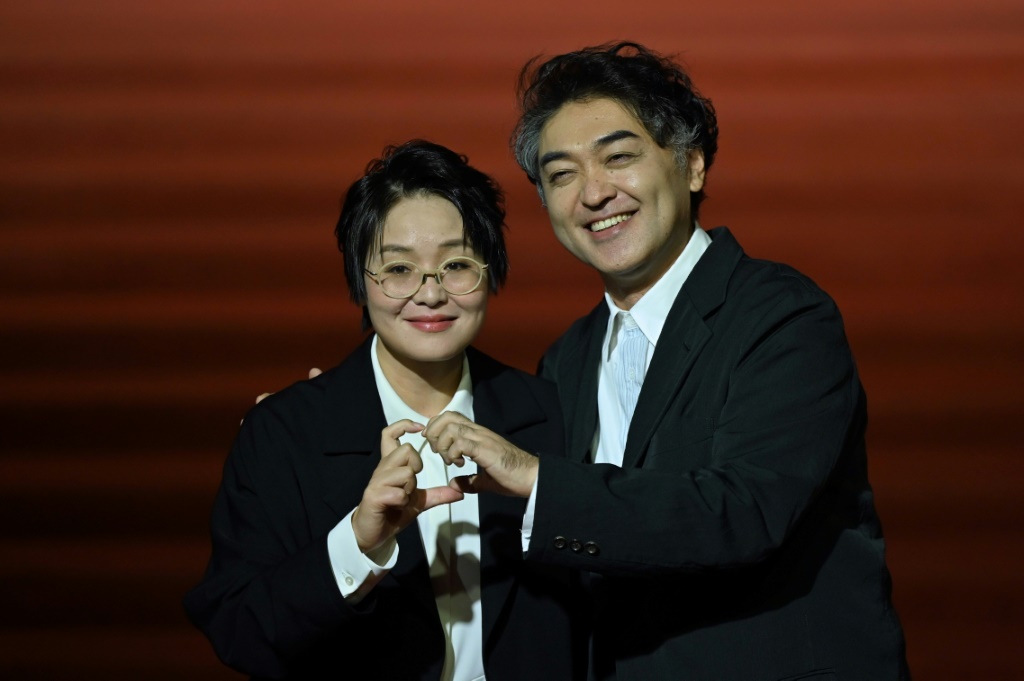 سارت المخرجة الصينية هوانغ جي (يسار) على السجادة الحمراء مع زوجها الياباني ريوجي أوتسوكا (يمين) (ا ف ب)