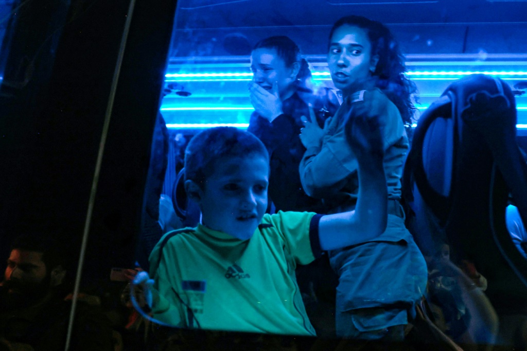 الرهائن الذين أطلقتهم حماس يظهرون من خلال نافذة الحافلة التي تنقلهم إلى قاعدة عسكرية في أوفاكيم جنوب إسرائيل، في المرحلة الثالثة من عمليات الإفراج (أ ف ب)   