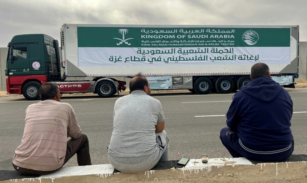 سائقون يجلسون إلى جانب شاحنات محملة بمساعدات سعودية ينتظرون في مدينة العريش المصرية القريبة من معبر رفح الحدودي مع غزة في 22 تشرين الثاني/نوفمبر 2023 (أ ف ب)  &nbsp;