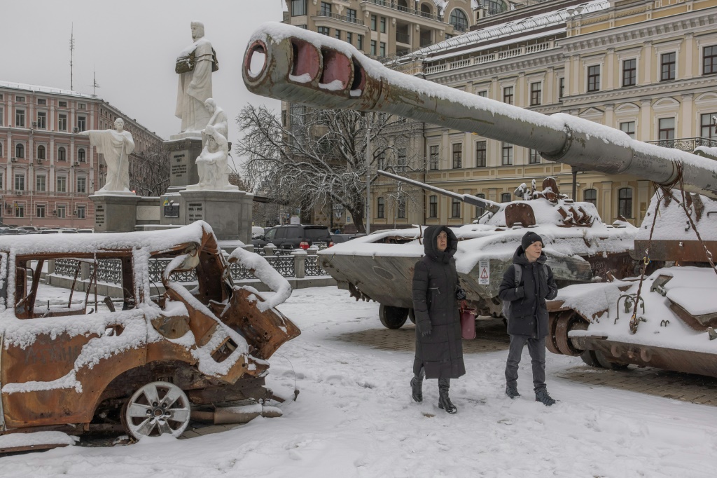 سكان كييف يسيرون أمام مركبات عسكرية روسية مدمرة مغطاة بالثلوج في وسط العاصمة الأوكرانية (أ ف ب)   