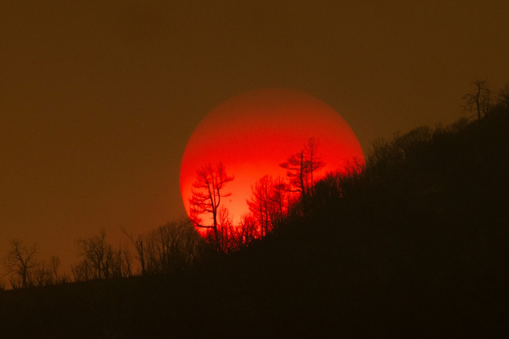 غروب الشمس خلف غابة محترقة بالقرب من ماريبوسا، كاليفورنيا (أ ف ب)   