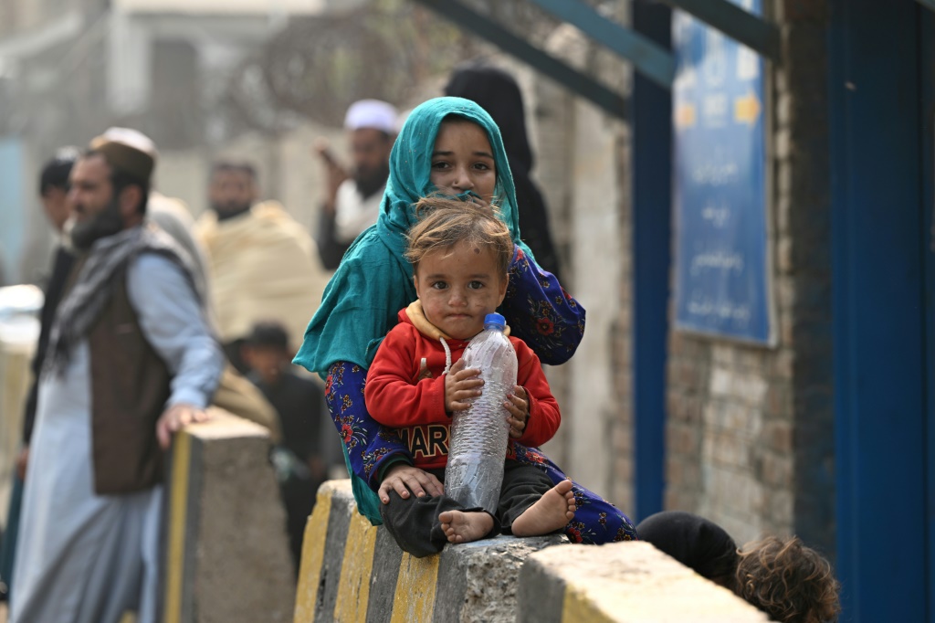 أطفال أفغان لاجئون يجلسون أمام مركز تابع للمفوضية السامية للأمم المتحدة لشؤون اللاجئين في ناوشيرا في 23 تشرين الثاني/نوفمبر 2023 (ا ف ب)