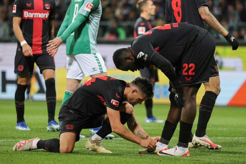 لاعب خط وسط باير ليفركوزن السويسري غرانيت تشاكا يربط حذاء زميله المهاجم النيجيري فيكتور بونيفاس خلال المباراة أمام فيردر بريمن في 25 تشرين الثاني/نوفمبر 2023 (ا ف ب)