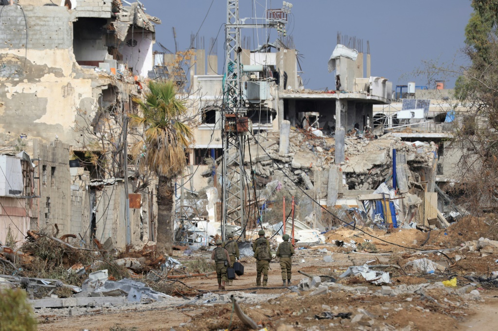جنود إسرائيليون يسيرون بجوار مبان مدمرة على طول طريق صلاح الدين الذي يربط شمال قطاع غزة بجنوبه في منطقة الزيتون على مشارف مدينة غزة في 28 تشرين الثاني/نوفمبر 2023 (أ ف ب)   