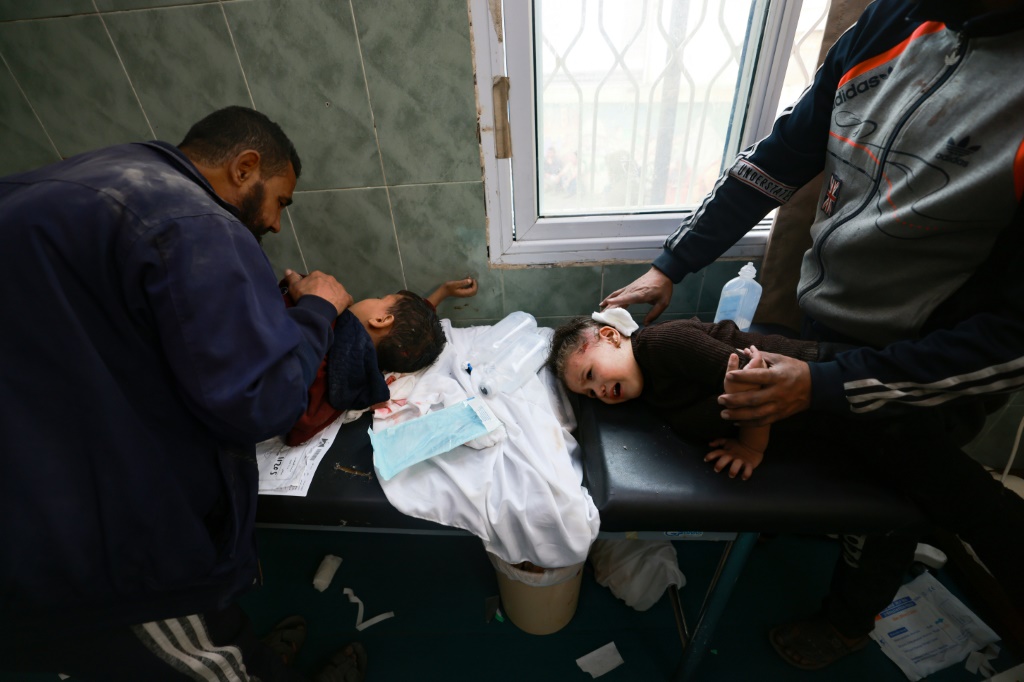 رجال يحاولون تهدئة أطفال صغار أصيبوا في غارة إسرائيلية على رفح في جنوب قطاع غزة في مستشفى النجار في الأول من كانون الأول/ديسمبر 2023 (ا ف ب)